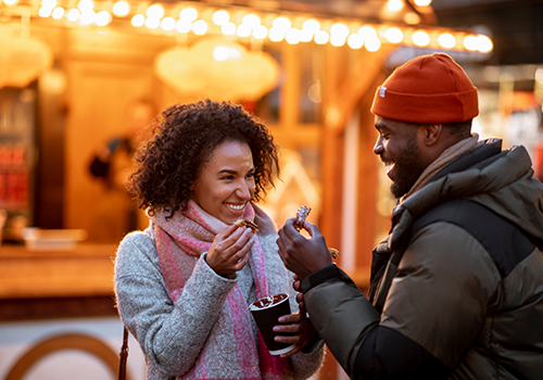 two friends eating sweet churros at the Xmas market