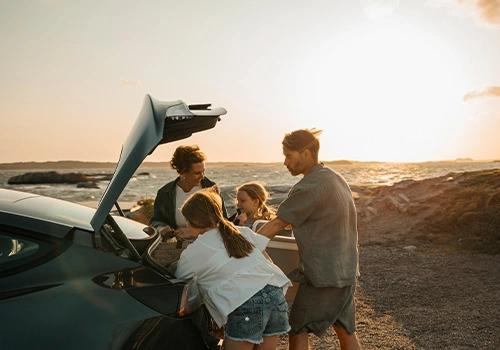 Family with kids loading the trunk close to the beach.