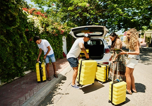 Grupo de viajantes a colocar malas no carro antes de começar uma road trip pelo Algarve.