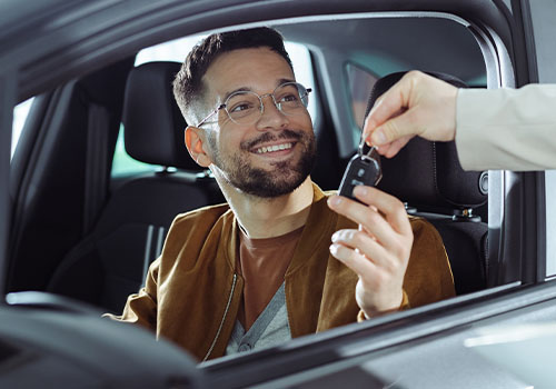 Homem dentro do carro a receber chave do carro