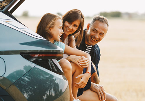 Happy family sitting in the trunk of the car