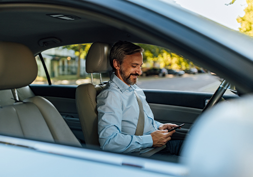 Homem dentro do carro de telemóvel na mão.