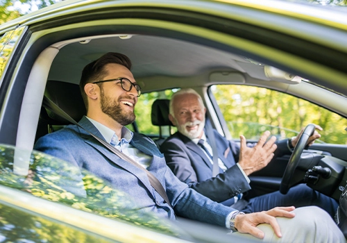  Two happy businessmen traveling by car on a business trip.