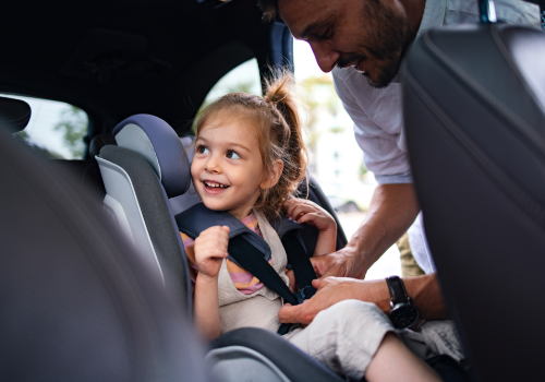  Father fastening his daughter into a child car seat