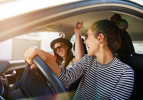 two young women driving along a street