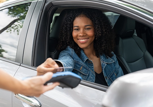 Cliente dentro de um carro a utilizar um cartão de cr&eacute;dito para formalizar o aluguer e bloqueio da caução.