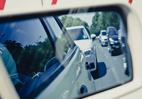 Rear-view mirror showing heavy traffic on a busy road