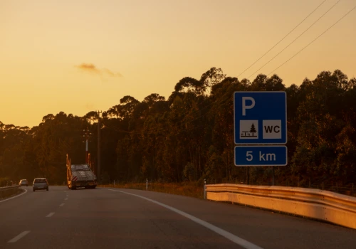 Highway in Portugal at sunset with road signs indicating a rest area.