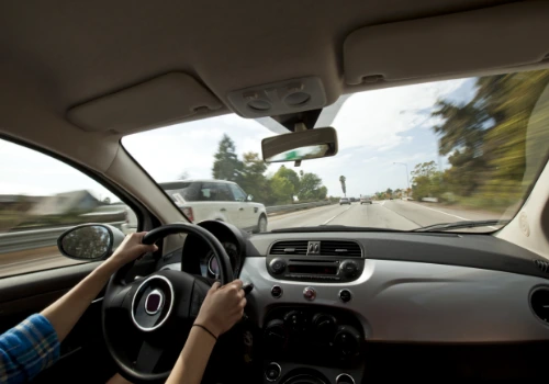 Female driver holding the steering wheel while driving on a highway.