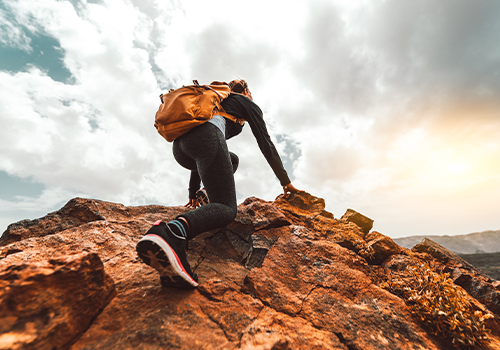 woman hiking on sunrise mountain peak