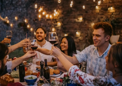 A happy group of friends raising their glasses of wine at an al fresco dinner, during a wine tourism experience in the Alentejo.