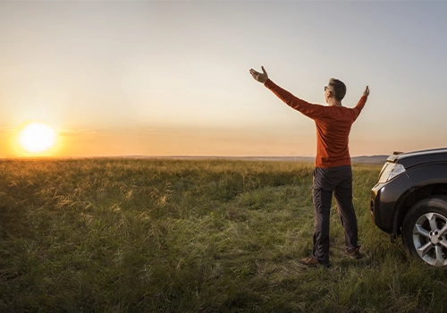 Pessoa junto ao carro, a desfrutar da liberdade de viajar por Portugal na época baixa.