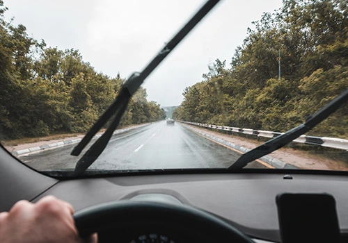 Escovas limpa-para-brisas do carro em funcionamento enquanto uma pessoa conduz.
