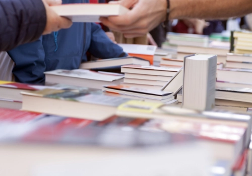 Outdoor book stalls at a book fair in Portugal, with visitors walking around