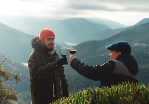 Two people toasting with wine beside a mountain landscape in Portugal.