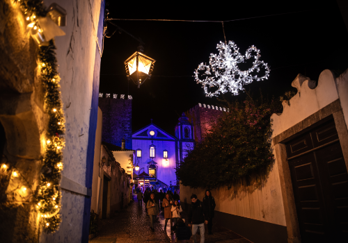 Visitors on a lit street in Óbidos during Vila Natal.