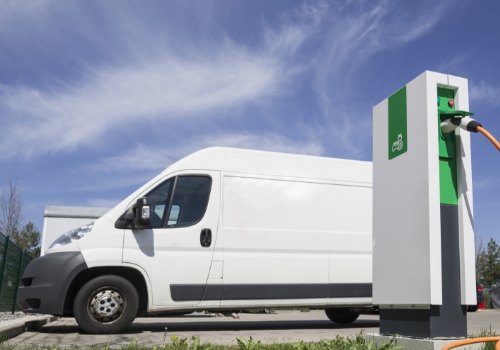 Veículo comercial estacionado junto de um ponto de carregamento elétrico