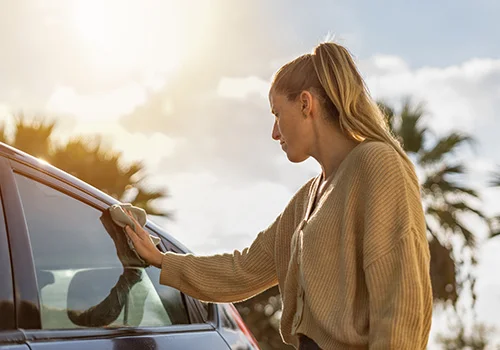 Person cleaning the exterior of a car after a long road trip to preserve the paintwork.