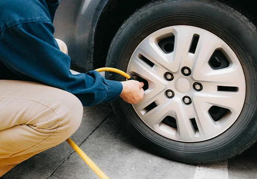 Driver checking tyre pressure with an air hose after driving many miles.
