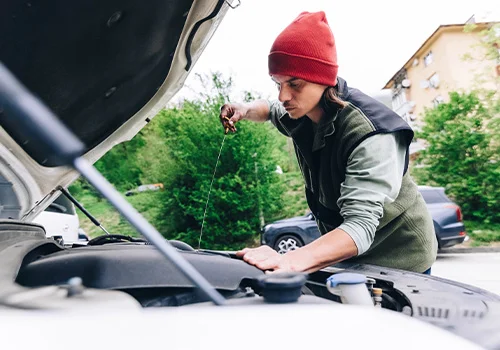 Person checking engine oil level with a dipstick after a long drive.