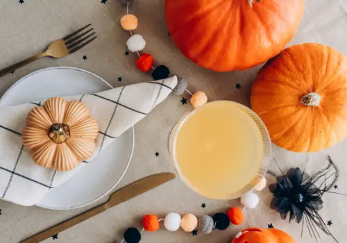 Mesa decorada para o Halloween, com abóboras, guirlanda de feltro e uma bebida em copo