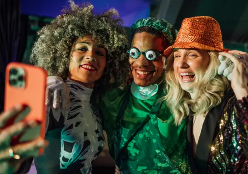 Três pessoas mascaradas a tirar uma selfie numa festa de Halloween