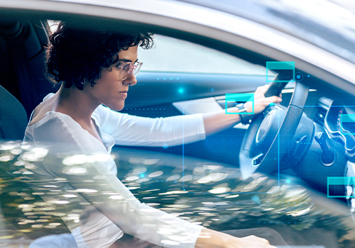 Young woman driving an autonomous car, illustrating car rental innovation and the role of new technologies in business mobility.