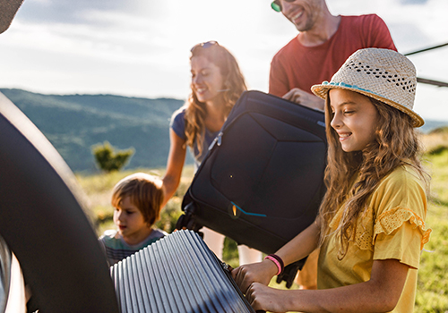 Família a colocar malas na bagageira do carro