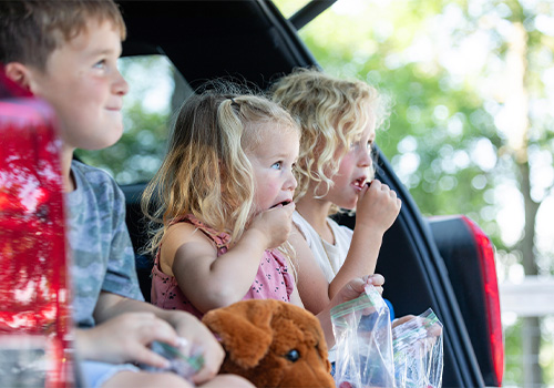 Children sitting in a car eating snacks