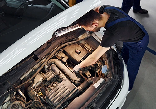 Technician carrying out preventive maintenance on the engine of a fleet vehicle with the bonnet open in a workshop, reducing breakdowns and operational costs.