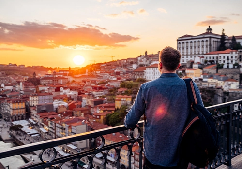 Man watching the sunset over Porto's historic centre, from the Dom Luís I Bridge