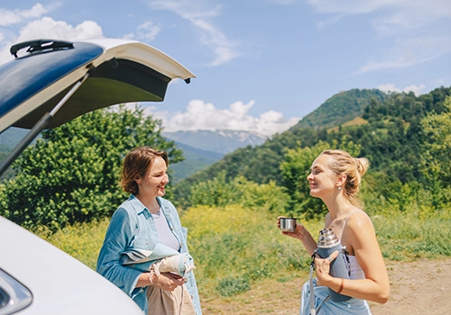 Amigas numa pausa da road trip perto do carro