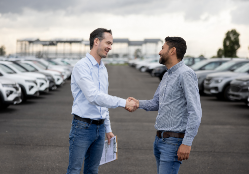 Comercial a apertar a mão a cliente no estacionamento de uma frota automóvel