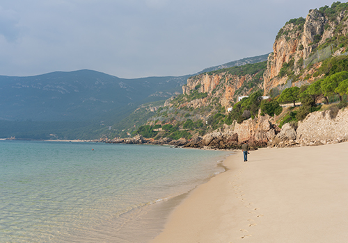Man walking along Figueirinha Beach in Arrábida Natural Park
