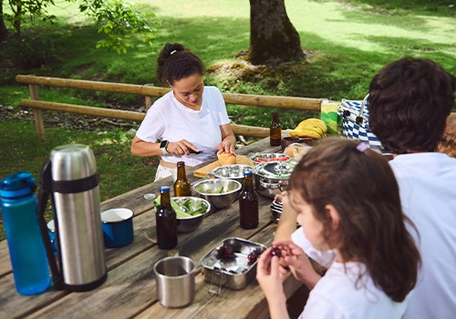 Family enjoying a picnic in a scenic green park during a sunny day in nature.