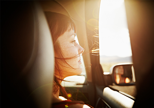 Woman with hair blowing looking out window of car