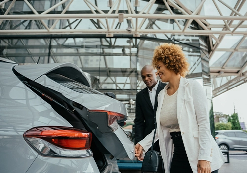 Two people loading luggage into a car's trunk 