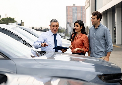 Sales representative explains the rental car protection options to a couple collecting their hire car.