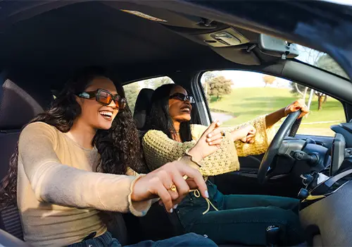 Duas jovens felizes num carro alugado a caminho de um concerto.