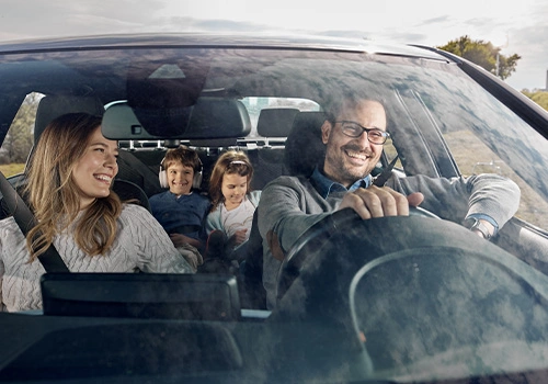 Família sorridente a caminho das f&eacute;rias da Páscoa num carro em movimento