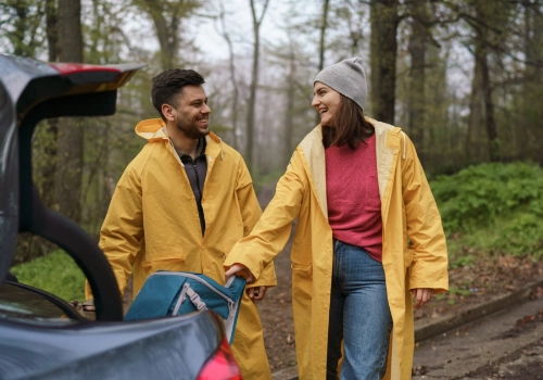 Group of friends with backpacks next to the car they are travelling in.