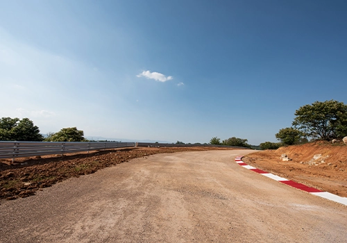 Estrada de terra de rally com curvas amplas e vegetação ao redor.