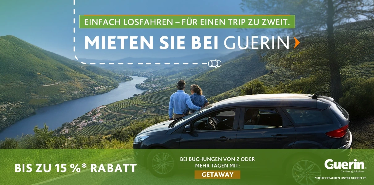 Paar sitzt neben einem Auto auf einem Aussichtspunkt mit Blick auf ein Tal und einen Fluss, mit Werbetext von Guerin: &bdquo;Mieten Sie bei Guerin&rdquo;, bis zu 15 % Rabatt auf Buchungen von 2+ Tagen mit dem Code GETAWAY